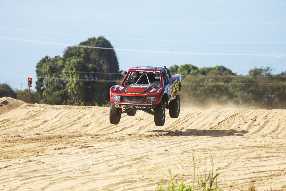 Off-road race truck jumping a sand rise at the Don River Dash 300 in Bowen